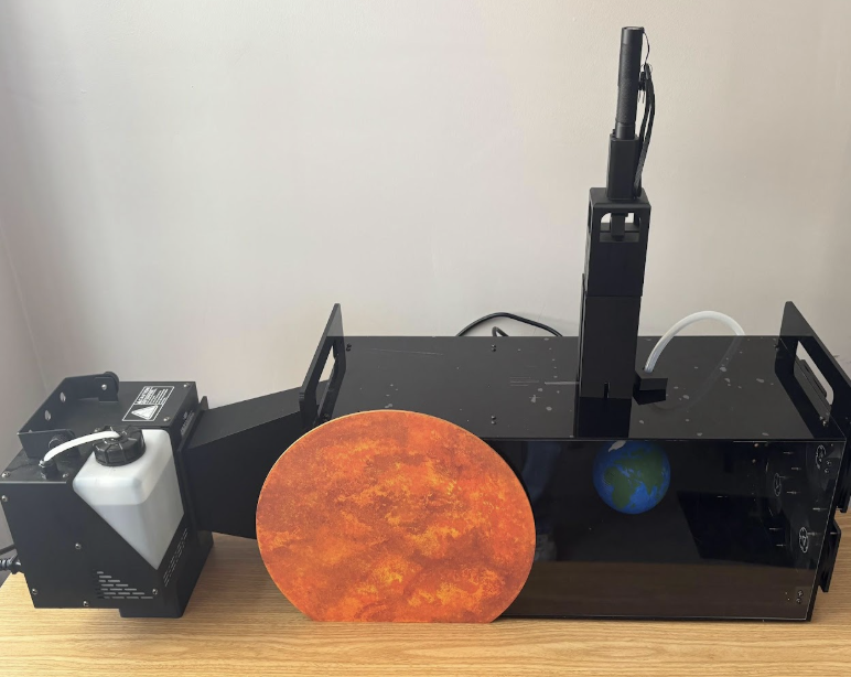 Setup of solar wind tunnel with fog machine, model Earth, laser mount and fans.