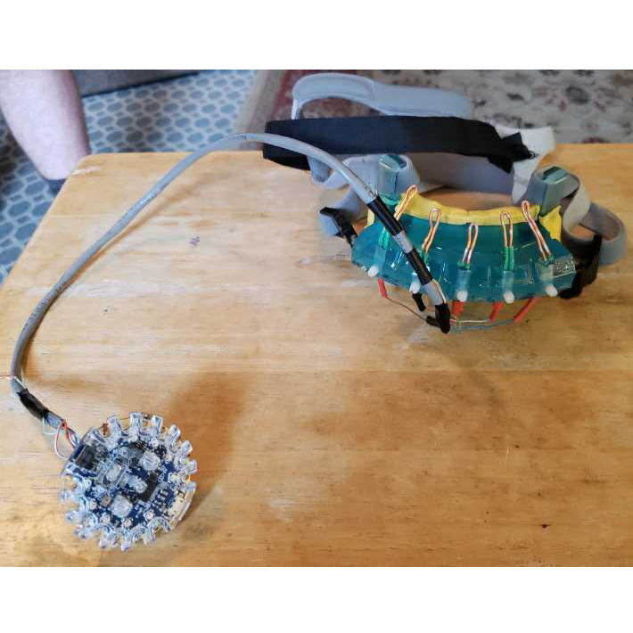 Circular microcontroller with wires running to headset that attaches on client's head.